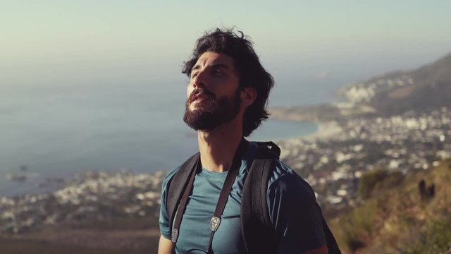 Hiker Shielding Eyes And Drinking Water On Mountain Against Sky