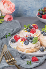 Mini pavlova cakes with fresh raspberries and blueberries.