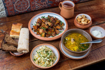 Middle Eastern cuisine dishes in ceramic plates on a wooden table. Soup with mushrooms and herb,...