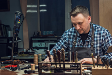 Man making leather wallet at a workshop. Concept of handmade craft production of leather goods.