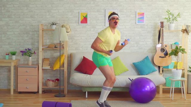 portrait of funny male athlete in 80s style engaged with dumbbells ,home workout