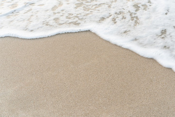 Smooth sandy at the beach and beautiful wave in background.