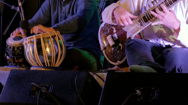 Two men playing traditional Indian tabla drums and sitar on stage of ethnic open air concert. Relaxation, meditative and traditional ethnic music concept