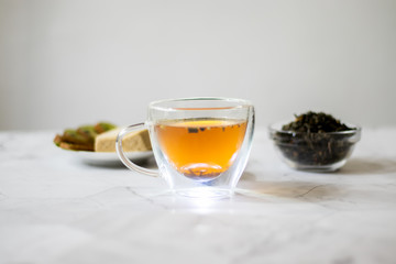 Green tea with jasmine in a transparent mug on a light background. Horizontal orientation