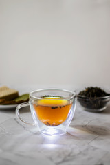 Green tea with jasmine in a transparent mug on a light background. Vertical orientation