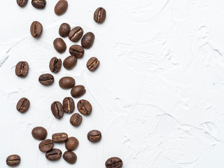 Coffee beans with copy space. Brown coffee beans on white concrete textured background. Top view or flat lay. Copy space.