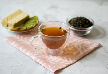 Green tea with jasmine in a transparent mug on a light background. Horizontal orientation