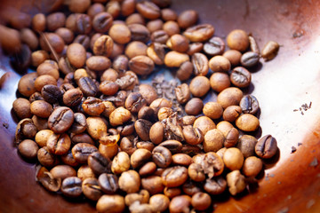Traditional hand craft coffee roasting in the brass pan with wooden spoon close up.