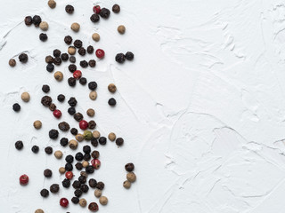 Assorted peppercorns. Medley trio colorful peppercorn on white textured concrete background with copy space. Top view or flat lay.