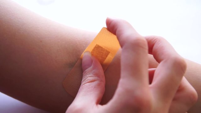 Putting on an adhesive plaster on fresh arm wound 