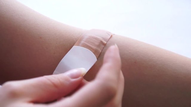 Putting on an adhesive plaster on fresh arm wound 