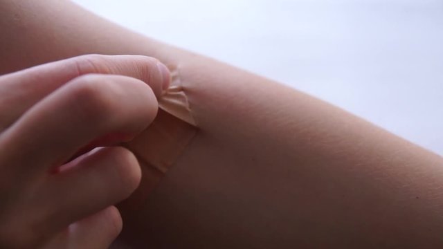 Removing an adhesive plaster from arm wound after blood test injection