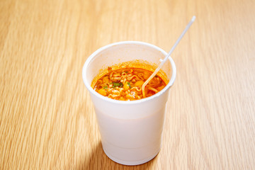 Hot and spicy instant noodle cup ready to eat on the wooden table close up.