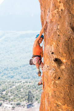 A girl in a helmet climbs a rock. © zhukovvvlad