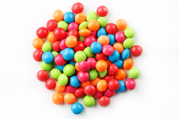 A rainbow of colors from multicolored candies close-up, multi-colored glaze dragee on a white background isolated