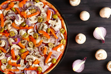 Italian pizza closeup on dark wooden background with mushrooms and vegetables, top view