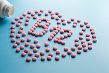 Pink tablets in the form of B12 in the heart on a blue background, spilled from a white can.