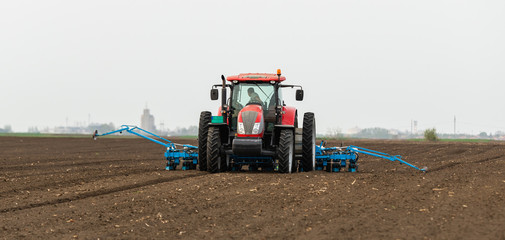 Fototapeta premium Farmer with tractor seeding soy crops at agricultural field