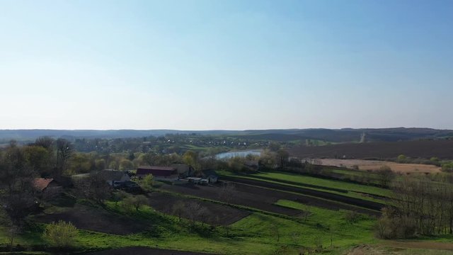Aerial flying over beautiful rural Europe landscape early spring with fields, buildings, ponds and trees. Sunset time, panoramic video 4k.