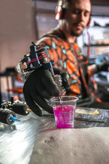 Hand of professional tattoo artist with a tattoo gun.