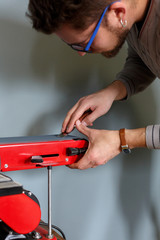 Leather craftsman sharpens knife for cutting leather on sander. Handmade concept. Concept of small business to create leather products.