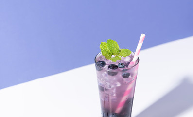 Cold and refreshing  blueberry punch cocktail with mint on purple background. summer drink