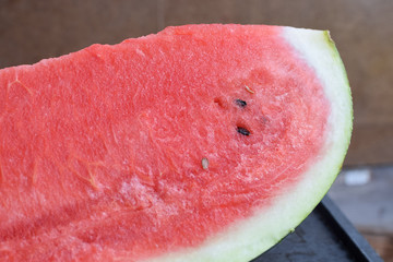 Slice of fresh red sweet watermelon with seeds in summer close up