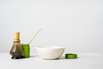 Front view of organic Japanese green tea and tools Chasen bamboo whisk, Chashaku spoon and bowl for brewing background with copy space