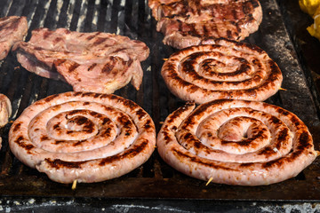 Obraz na płótnie Canvas Round sausages being cooked on a hot grill at a street food festival