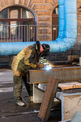 welder working with full protective equipment on the street of the city of St. Petersburg.