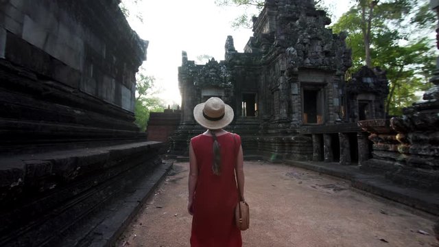 Woman in red dress exploring the Chau Say Tevoda temple (Angkor Wat compelx) dedicated to Shiva and Vishnu with unique types of female sculptures of devatas enshrined in it. Cambodia
