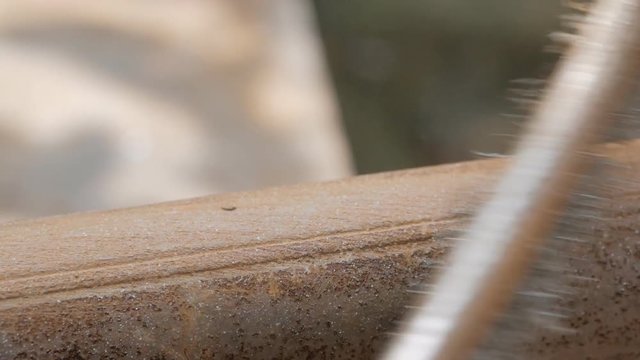 Close-up of a man's hands in work gloves, cleaning the old pipe from rust with a metal brush.