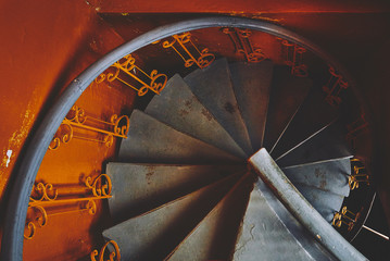 gray spiral staircase in an old orange train, in ocher style, close-up of spirals and descending lines of steps