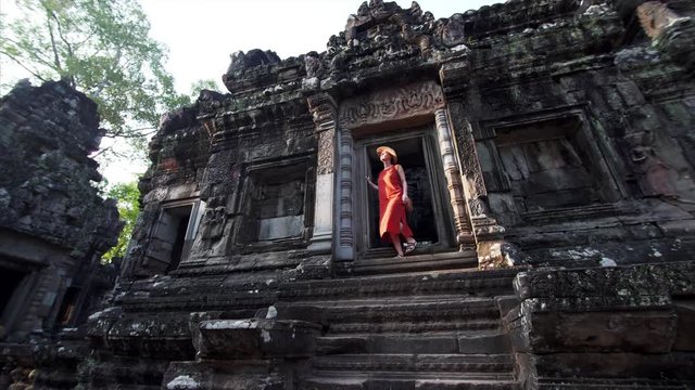 Sliding view from below of woman coming out from the Chau Say Tevoda temple and looking around. Angkor Wat complex, Cambodia