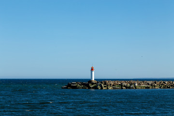 White lighthouse tower on blue sky background