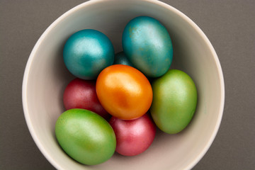Colorful easter eggs in bowl,on grey background. Pearl easter eggs. Top view. Easter greetings, recipe.