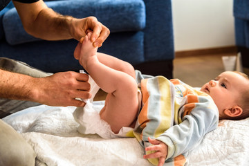 Affectionate father playing with his baby while he changes the disposable diaper.