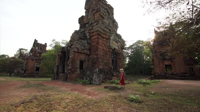 Sliding view of woman exploring ruins of Prasat Suor Prat, a series of twelve towers in Angkor Wat complex, made from rugged laterite and sandstone. Cambodia