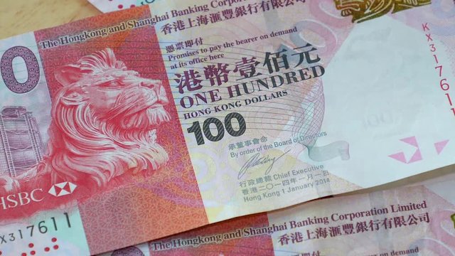 Slow motion 100 Hong Kong Dollars banknote, HKD money falling on wood table