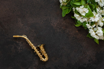 Little Golden saxophone and blossoming apple tree  branches. Top view, close-up on dark background