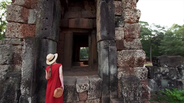 Woman is exploring interior of Prasat Suor Prat, a series of twelve towers in Angkor Wat complex, made from rugged laterite and sandstone. Cambodia
