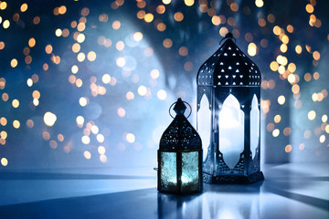 Couple of glowing Moroccan ornamental lanterns on the table. Greeting card, invitation for Muslim...