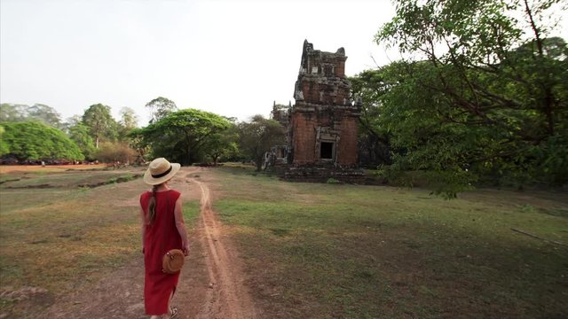 Following the woman who is exploring ruins of Prasat Suor Prat, a series of twelve towers in Angkor Wat complex, made from rugged laterite and sandstone. Cambodia