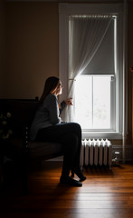 Woman sitting in chair looking out window in room
