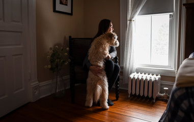 Woman and dog looking out of bedroom window