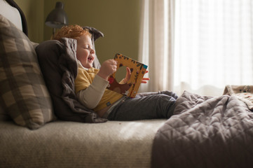 Young boy sitting on bed and looking at book