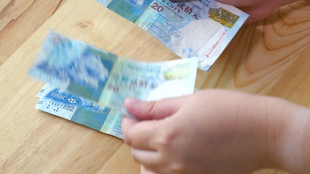 Woman hand counting 20 Hong Kong Dollars banknote, HKD money on wood table