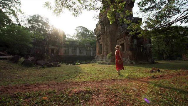 Picturesque view of woman exploring Prasat Suor Prat towers under beautiful sunshine. It's a series of twelve towers in Angkor Wat complex, made from rugged laterite and sandstone. Cambodia