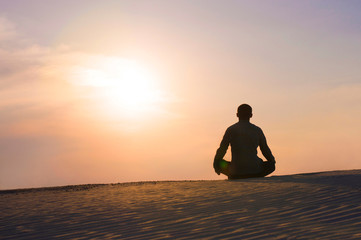 man in the lotus position at sunset