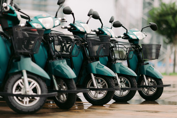blue moped scooters for sale or rent parked in a row at parking